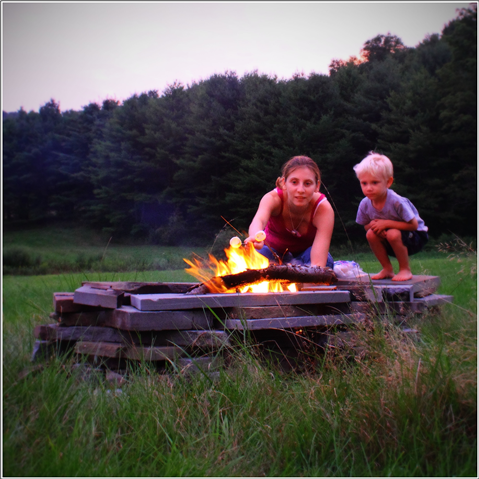 Second Place Winner - Roasting Marshmallows - Photographer: Justin. Young woman roasting marshmallows over a fire with a young boy child.