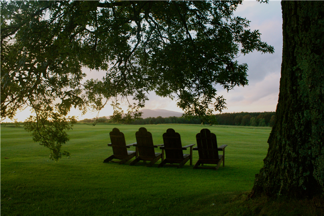 Second Place Winner: Crystal Lake, Susquehanna County; photo by Erika Bruckner. Wooden lawn chairs facing a mountain on the horizon, with a large tree in the foreground.