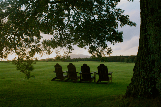 Second Place Winner: Crystal Lake, Susquehanna County; photo by Erika Bruckner. Wooden lawn chairs facing a mountain on the horizon, with a large tree in the foreground.